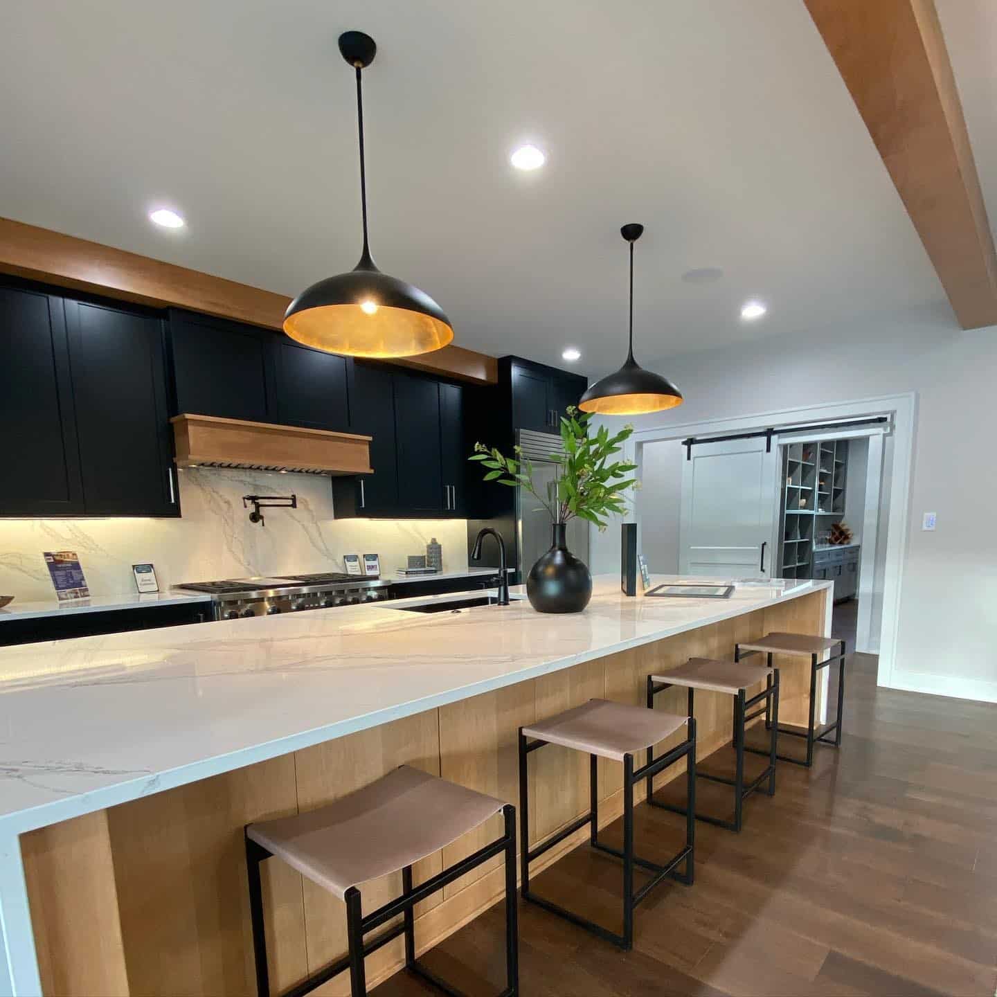 15. Modern Black Kitchen with Wood Island and Warm Lighting - black and wood kitchen ideas