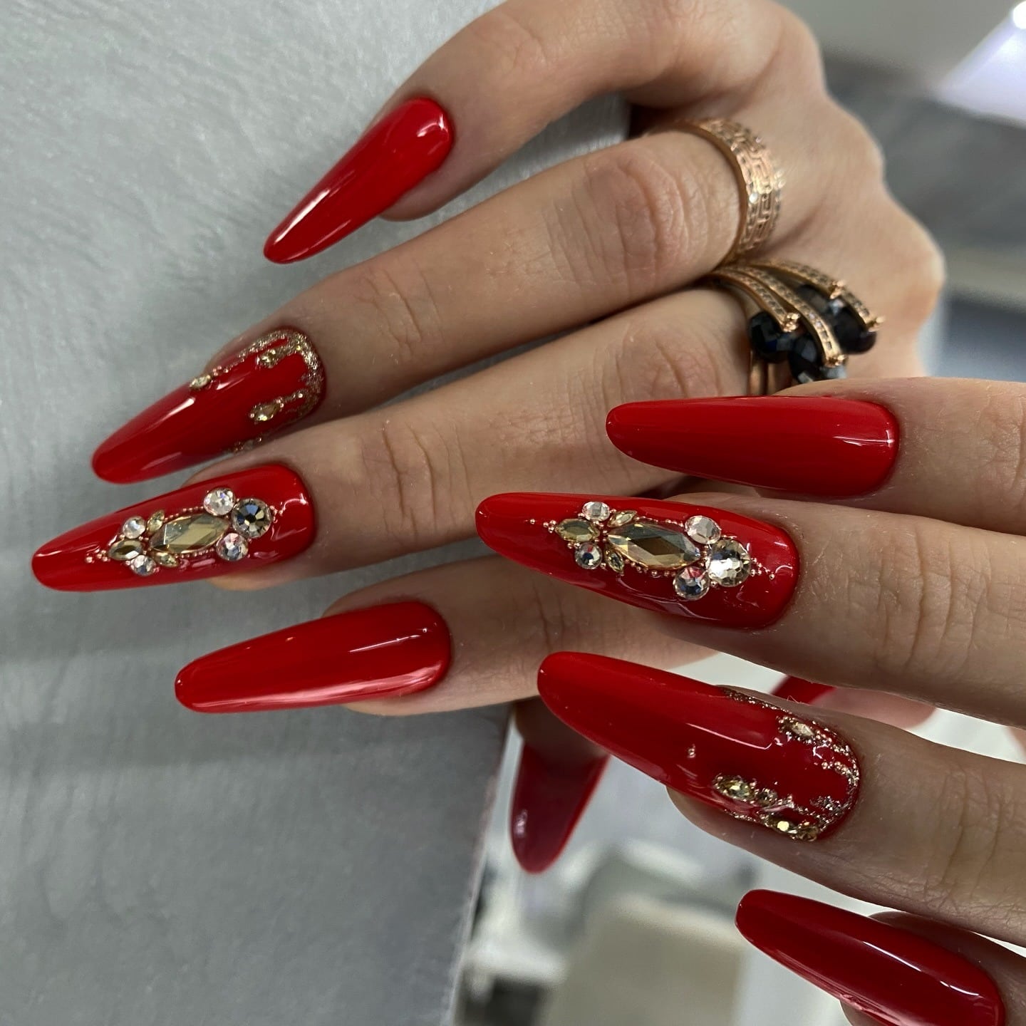 8. Embellished Red Stiletto Nails with Gold Detailing - red nail ideas