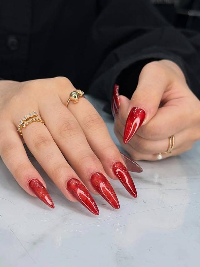 13. Shimmer Red Stiletto Nails with Gloss Overlay - red nail ideas