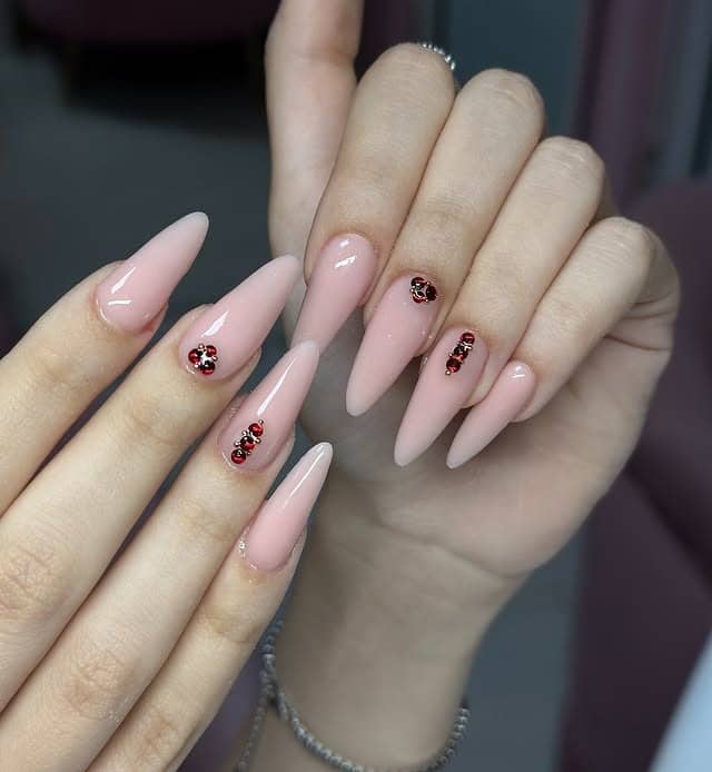 11. Blush Pink Stiletto Nails with Ruby Crystal Accents - old money nail ideas