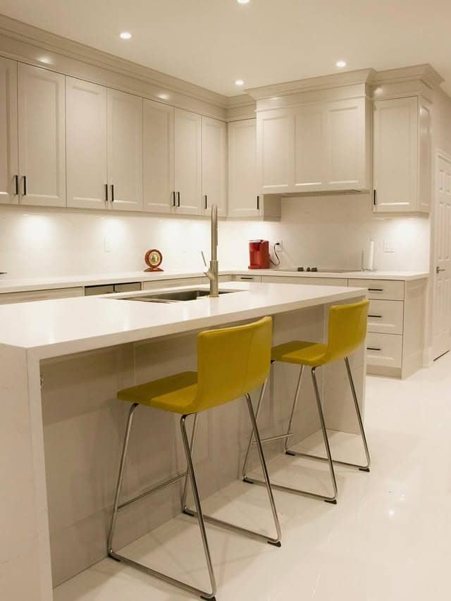 11. Minimal Cream Kitchen with Bright Accent Seating - cream kitchen cabinet ideas