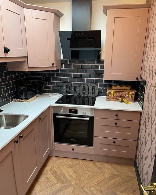 11. Mauve Pink Compact Kitchen with Dark Tile Contrast - pink kitchen ideas