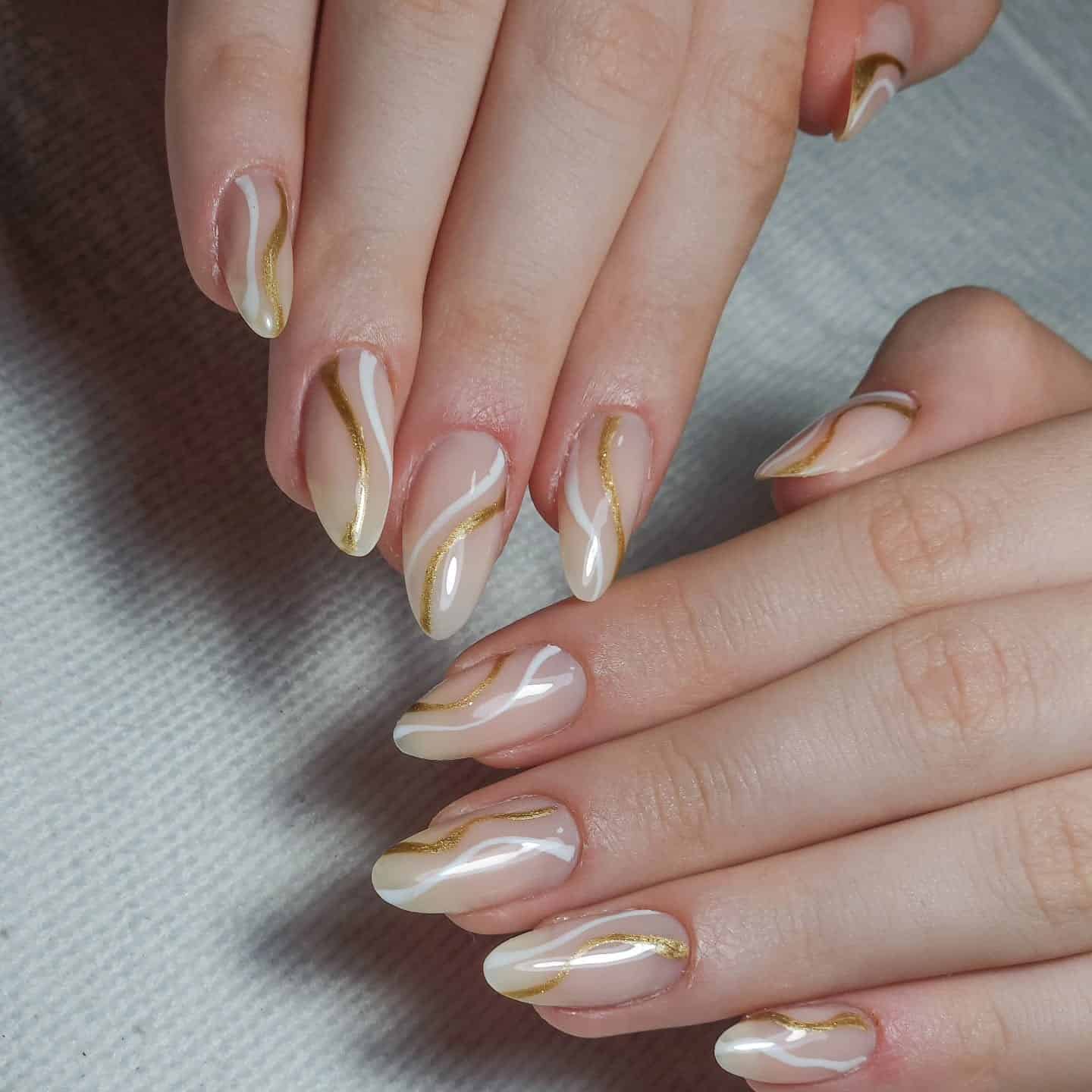 1. Nude Almond Nails with White and Gold Flow Lines - lines nail ideas
