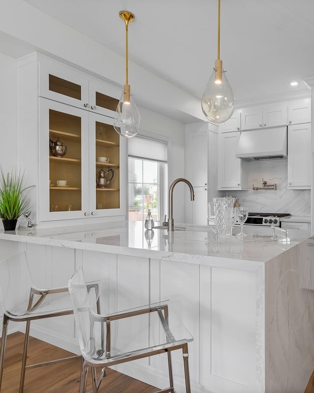 15. Crisp White Kitchen with Glass Lighting and Subtle Marble Countertops - white countertop kitchen ideas