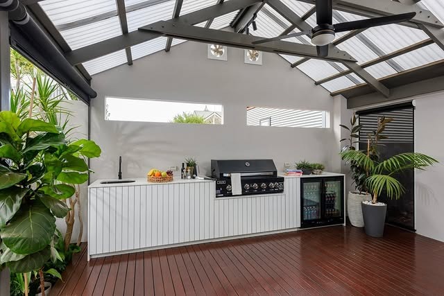 7. Bright Indoor-Outdoor Kitchen with White Paneling and Natural Wood Flooring - outdoor kitchen ideas