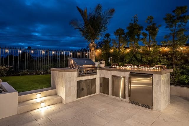 17. Evening Outdoor Kitchen with Soft Lighting and Neutral Stone Palette - outdoor kitchen ideas