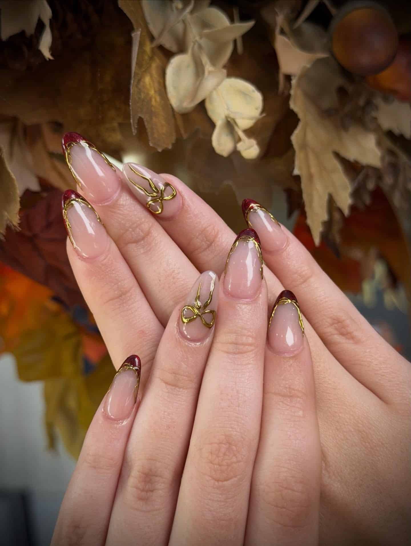 12. Burgundy French Tip with Gold Outline Bow Accent Nails - christmas dip nail ideas