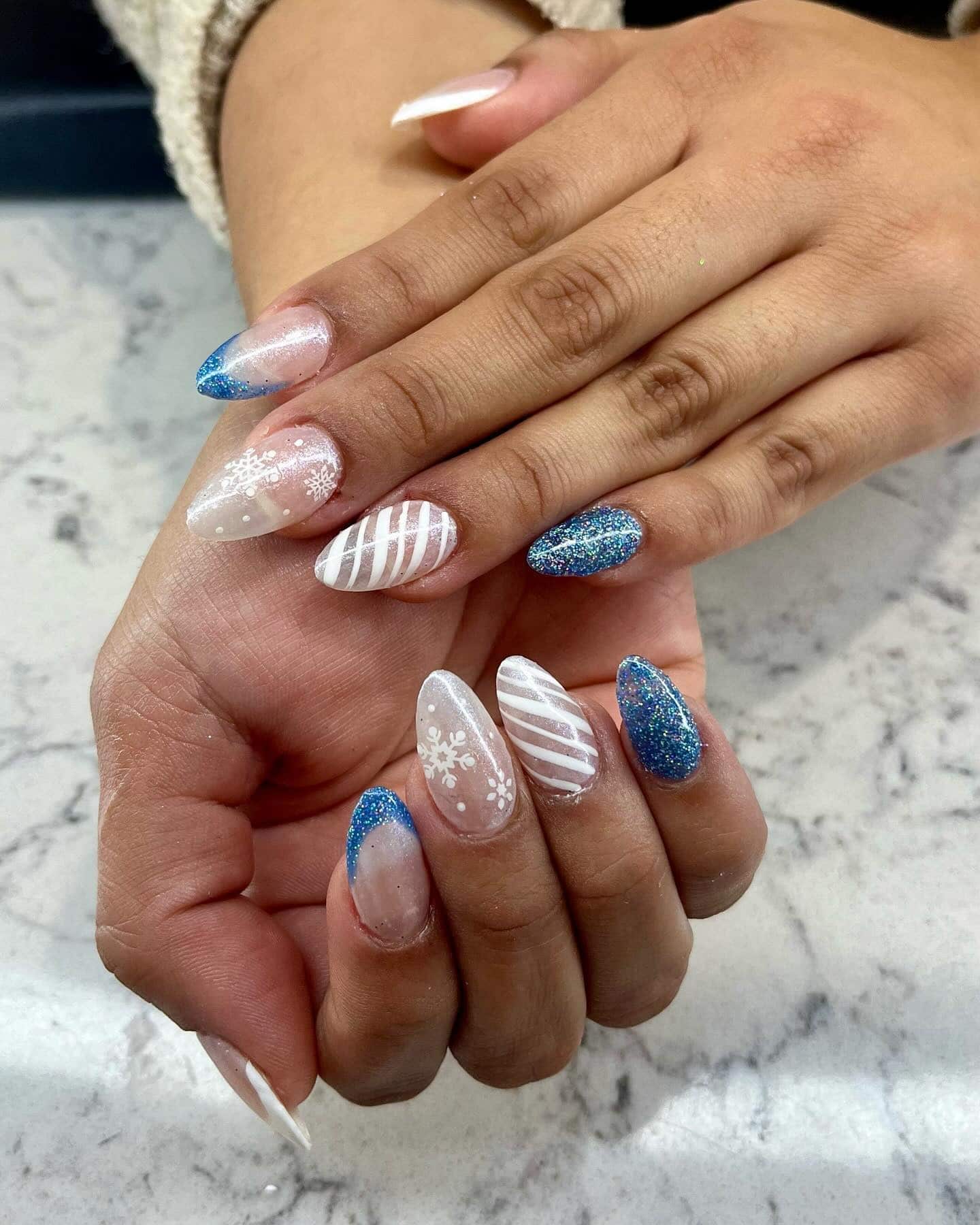 19. Blue Glitter and White Snowflake Almond Nails - christmas dip nail ideas