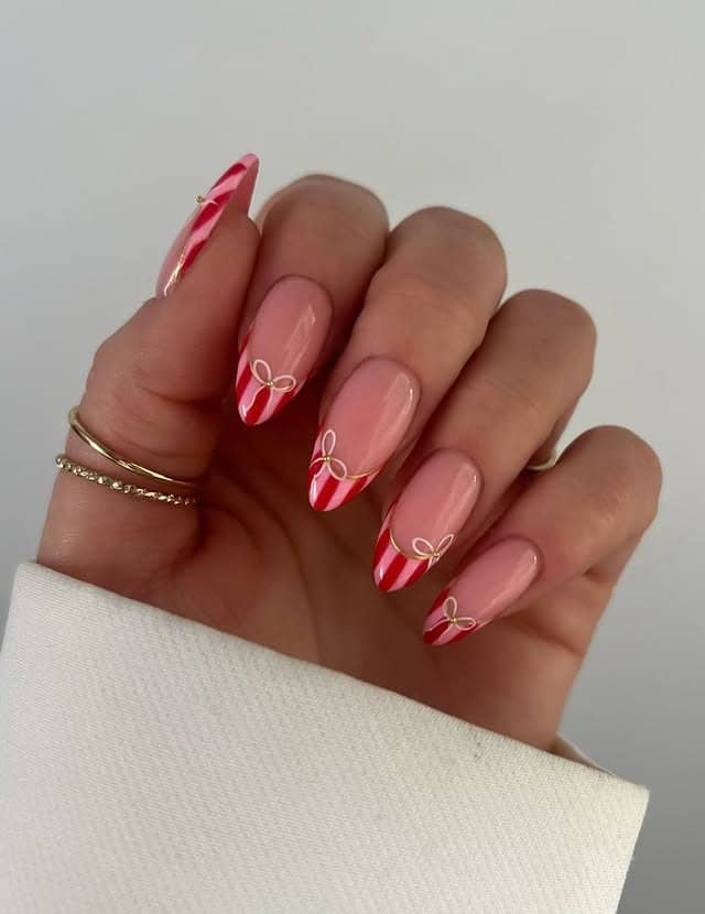 22. Candy Cane French Tip Almond Nails with Gold Bow Detail - christmas dip nail ideas