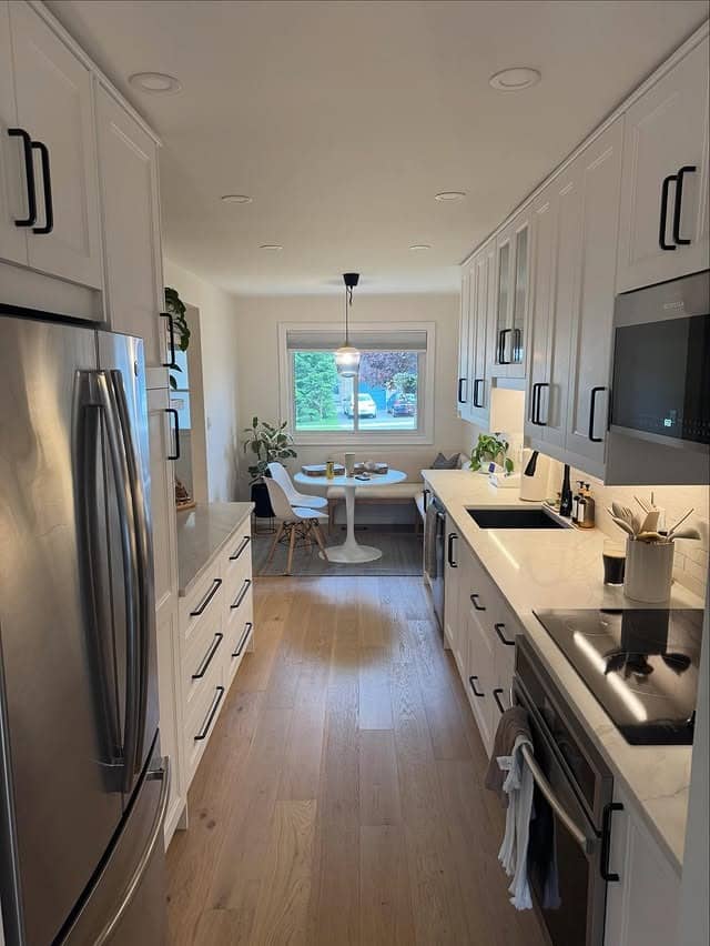 14. Minimal White Galley Kitchen with Light Wood Flooring - galley kitchen ideas