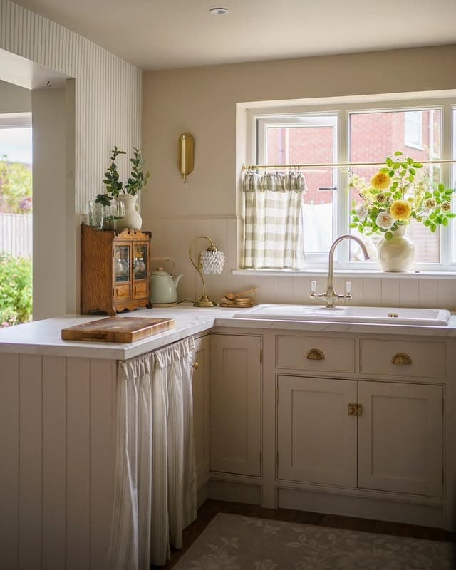 21. Soft Beige Country Kitchen with Skirted Sink and Vintage Accents - country style kitchen ideas