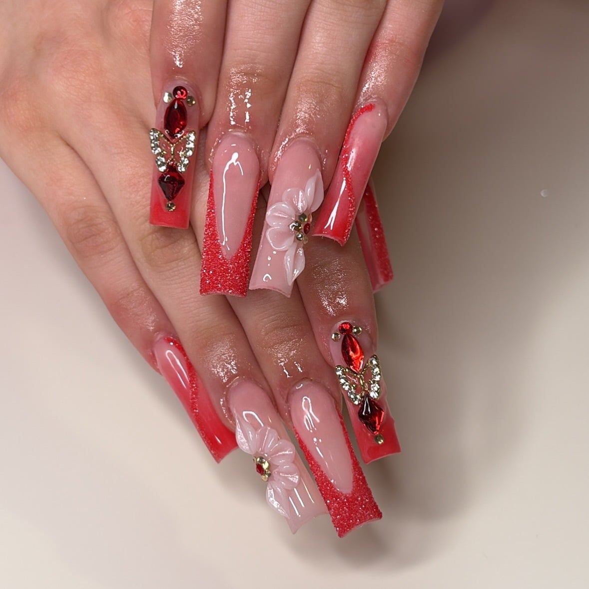 15. Red Glitter French Tip Nails with Butterfly Charm and 3D Floral Art - red prom nail ideas