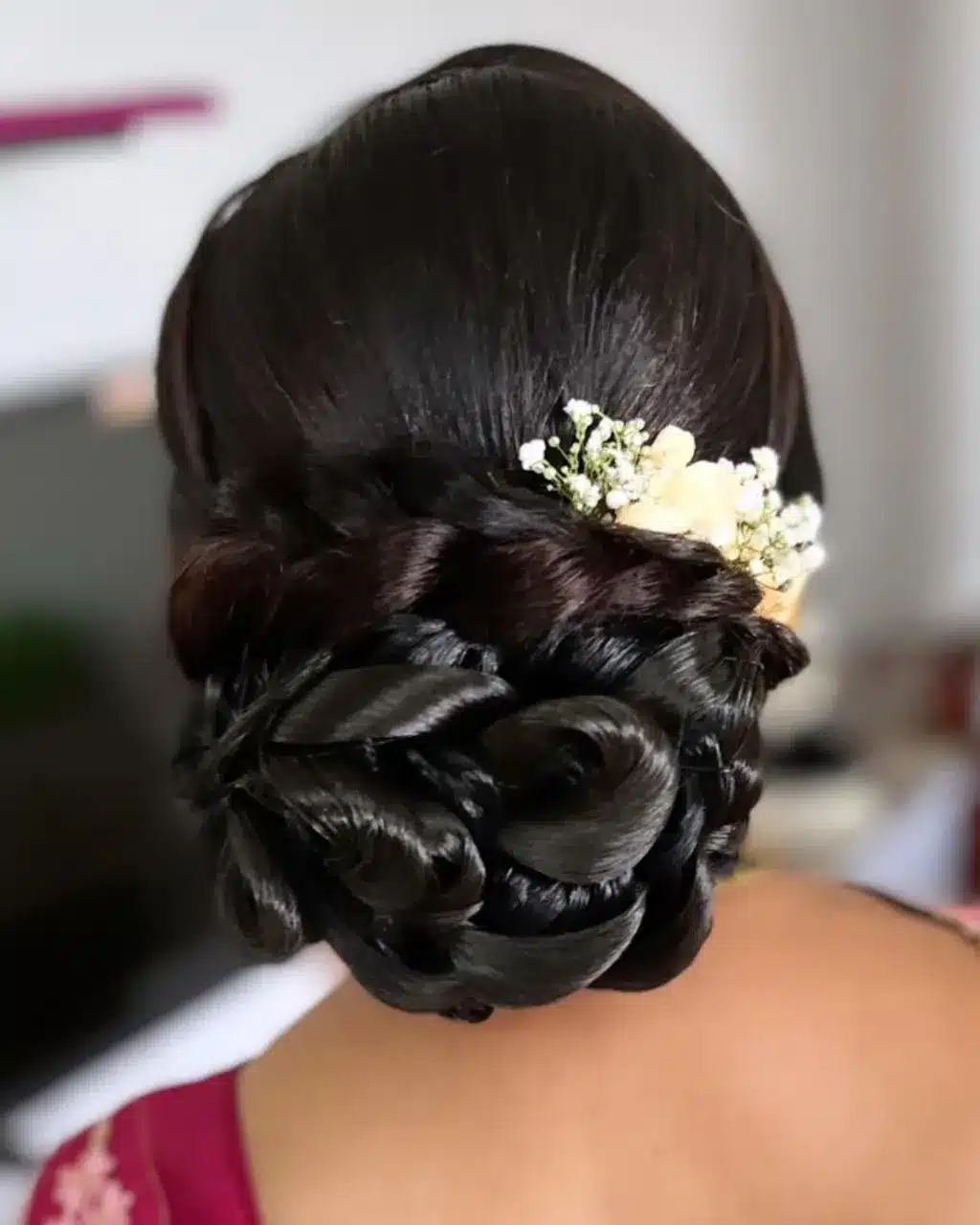 2. Sleek Espresso Gloss Rolled Bun with Floral Accent - Messy Bun Hairstyles