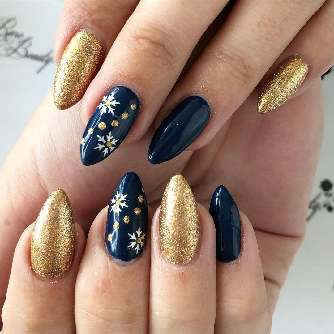 2. Navy and Gold Snowflake Almond Nails - navy and gold nail ideas