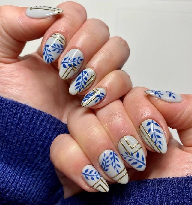 12. Blue Botanical and Gold Line Almond Nails - navy and gold nail ideas