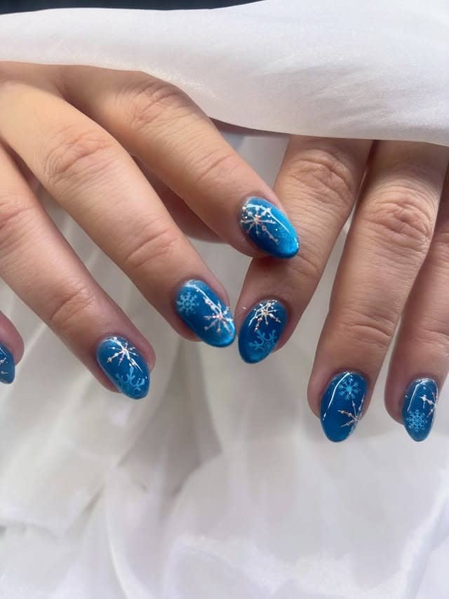 21. Sapphire Blue Snowflake Oval Nails - winter nail ideas