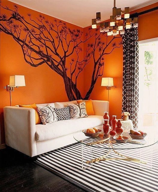 5. Bold Orange Statement Wall with Artistic Tree Mural - orange living room ideas