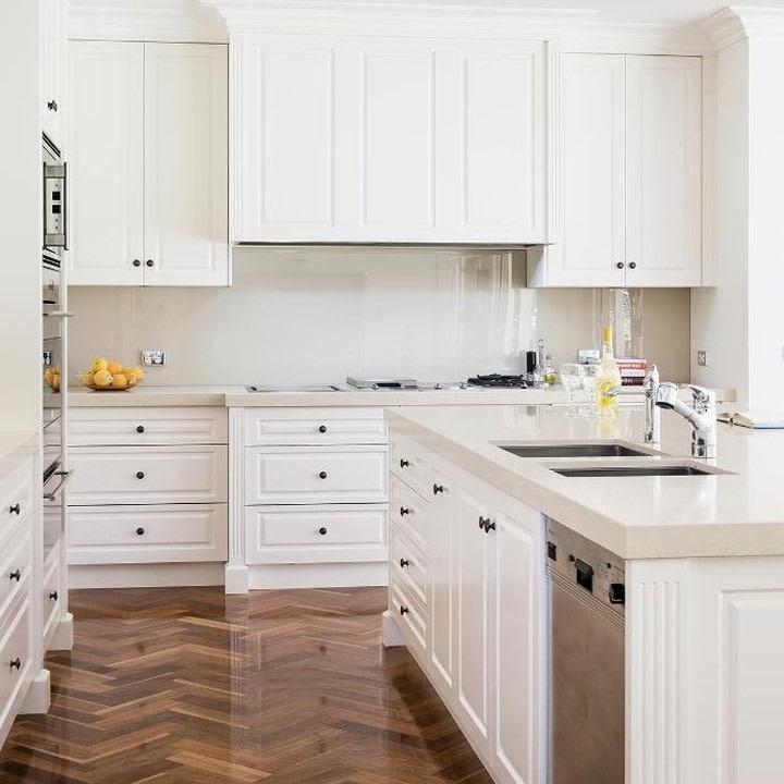 18. Elegant White Kitchen With Herringbone Wood Floors - white kitchen ideas