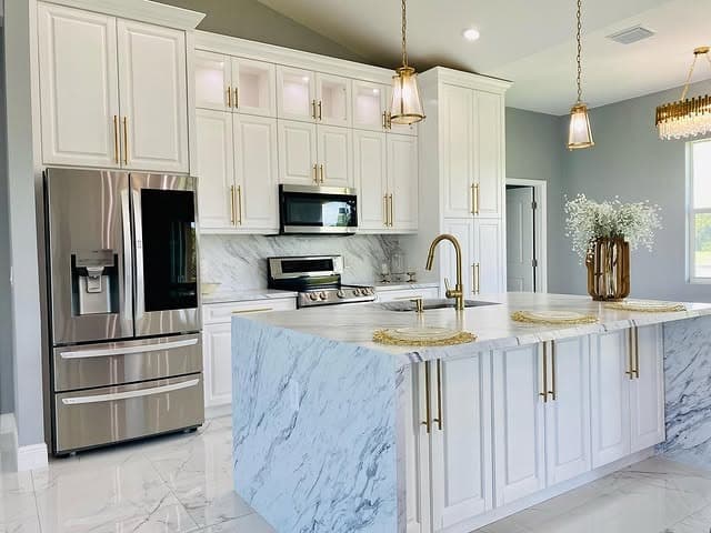 22. White Marble Kitchen With Gold Waterfall Island - white and gold kitchen ideas