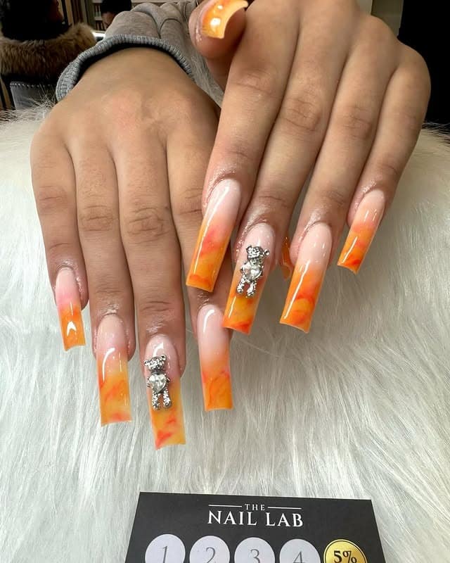 13. Orange Marble Ombre Coffin Nails with Crystal Accents - orange color nail ideas