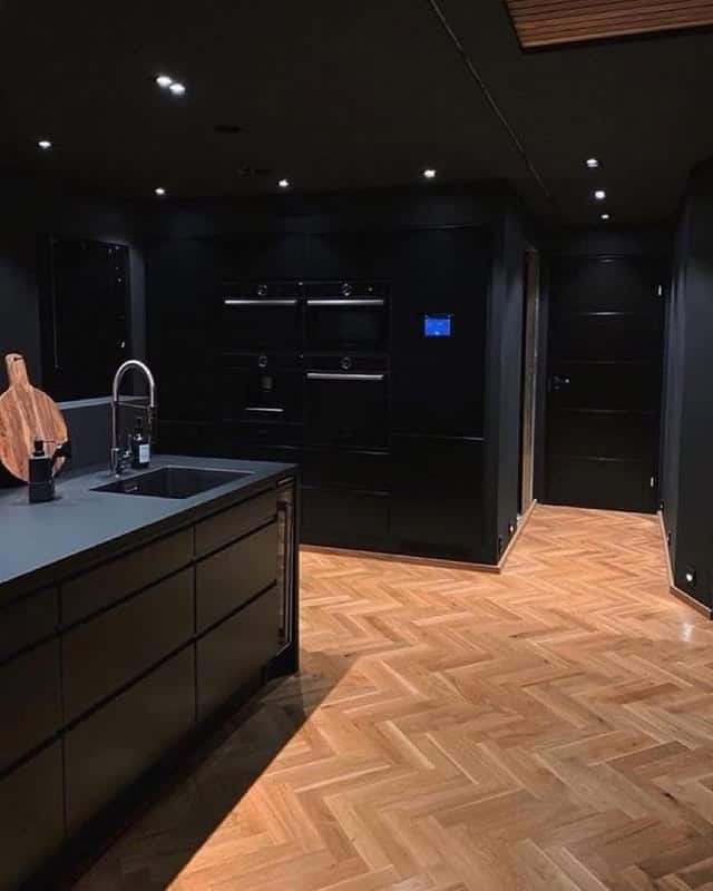 12. Matte Black Kitchen with Herringbone Wood Flooring - dark kitchen ideas