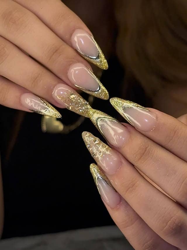 7. Gold Glitter Stiletto Nails with Black Accents - gold nail ideas