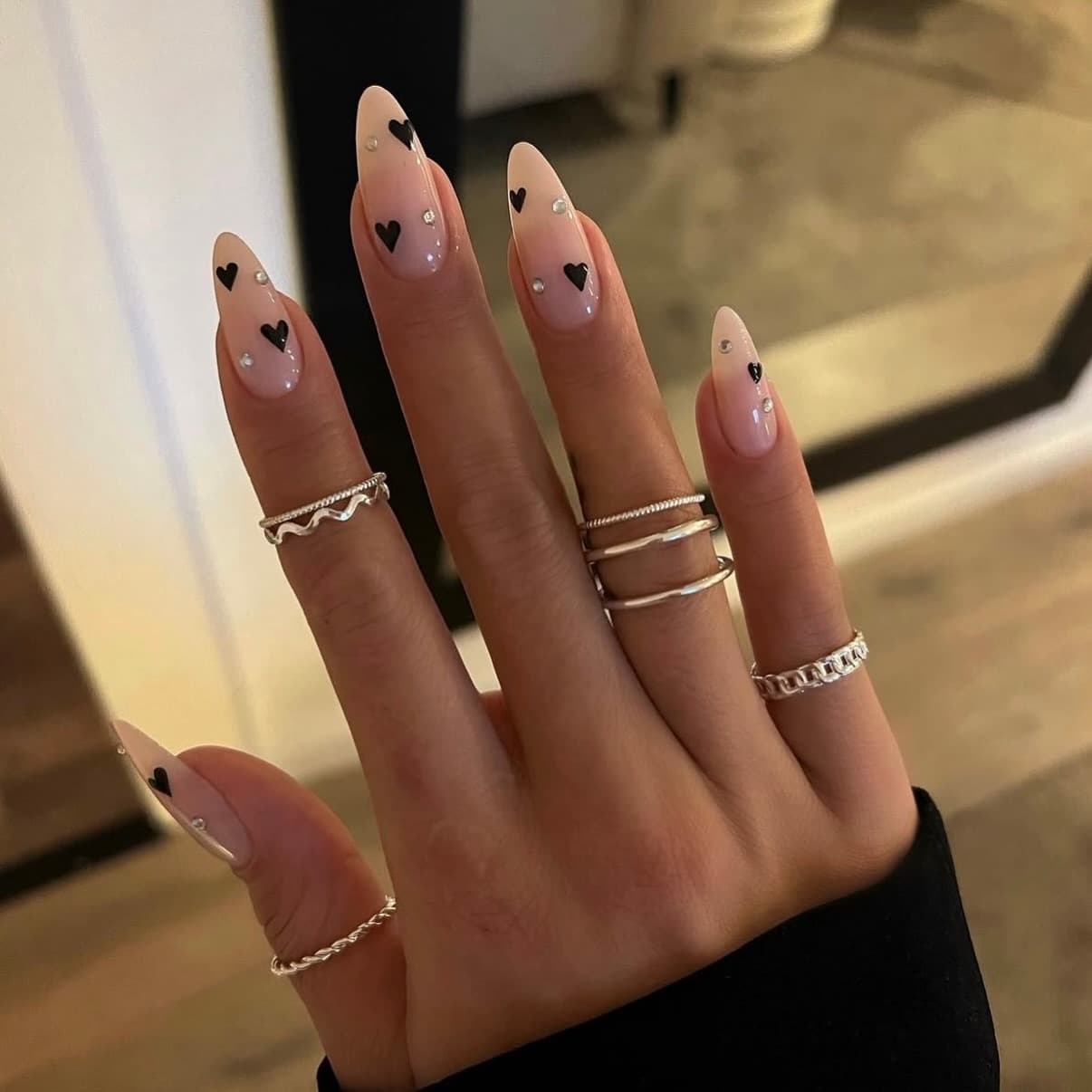 7. Nude and Black Heart Rhinestone Almond Nails - heart nail ideas
