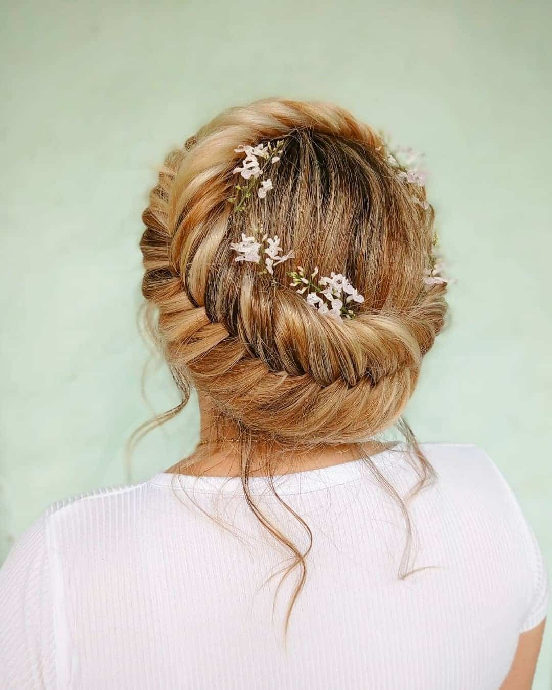 11. Honey Blonde Crown Braid Low Bun with Floral Accents - Crown Braid Hairstyles