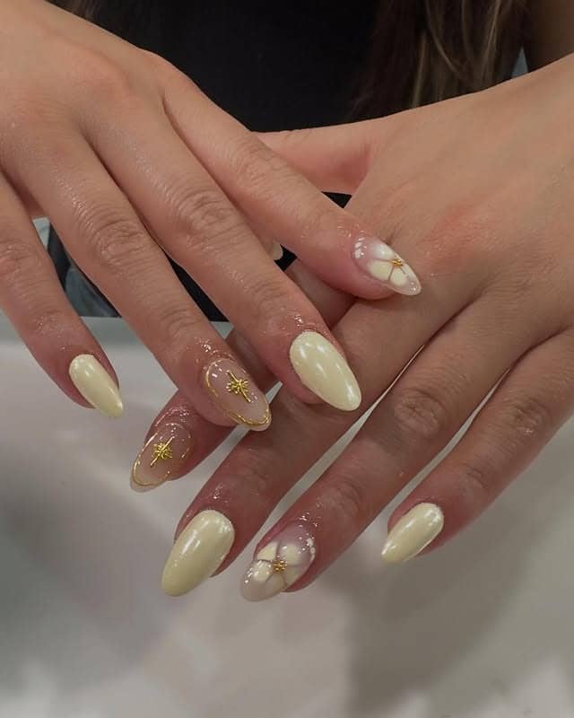 2. Ivory Floral Almond Nails with Gold Details - trendy simple nail ideas