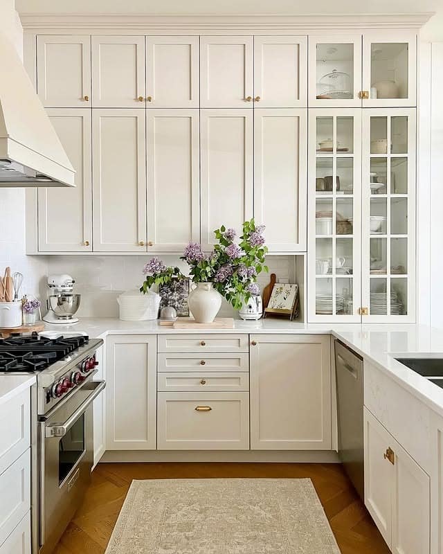 21. Creamy White Cabinets with Glass Displays and Warm Brass - white cabinets kitchen ideas