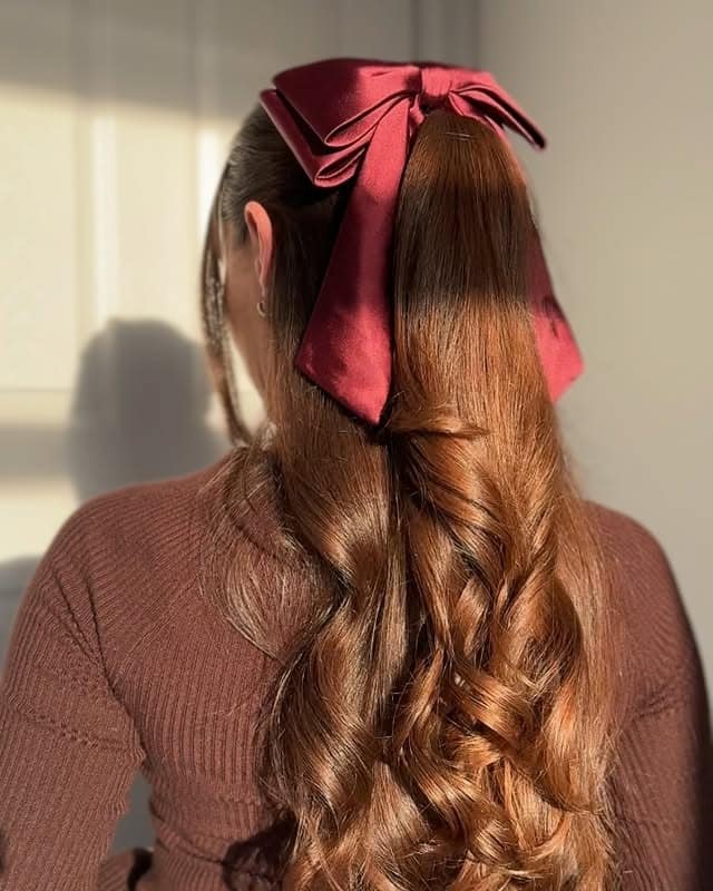 11. Copper Brown Curled Ponytail with Satin Bow - Winter Hairstyles