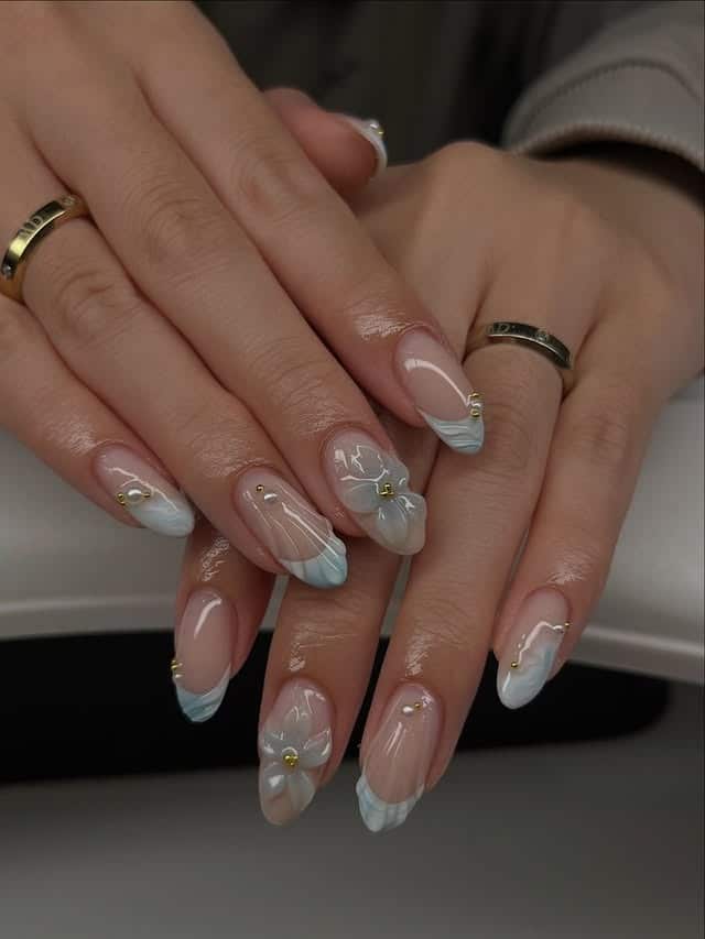 8. Icy Blue French Tip Nails with White Floral Accents - aesthetic nail ideas