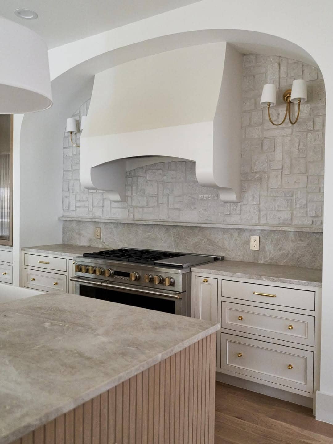 17. French Country Light Gray Stone Kitchen Feature Wall with Brass Sconces - feature wall kitchen ideas