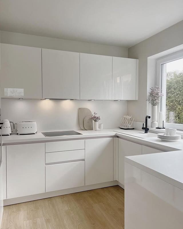 15. Minimalist Glossy White Kitchen with Warm Wood Flooring - all white kitchen ideas