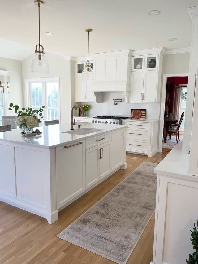 22. Timeless White Kitchen with Warm Wood Flooring and Brass Accents - all white kitchen ideas