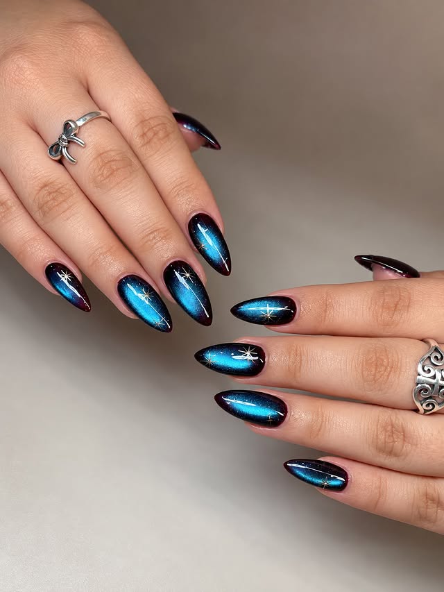 19. Electric Blue and Black Cat Eye Galaxy Almond Nails - galaxy nail ideas
