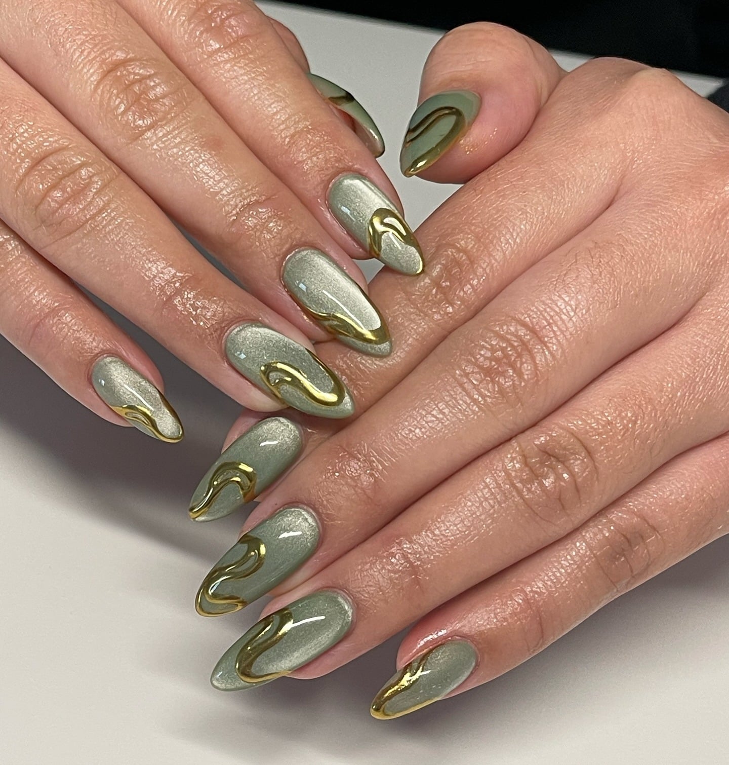 6. Metallic Sage Green Almond Nails with Gold Swirls - green and gold nail ideas